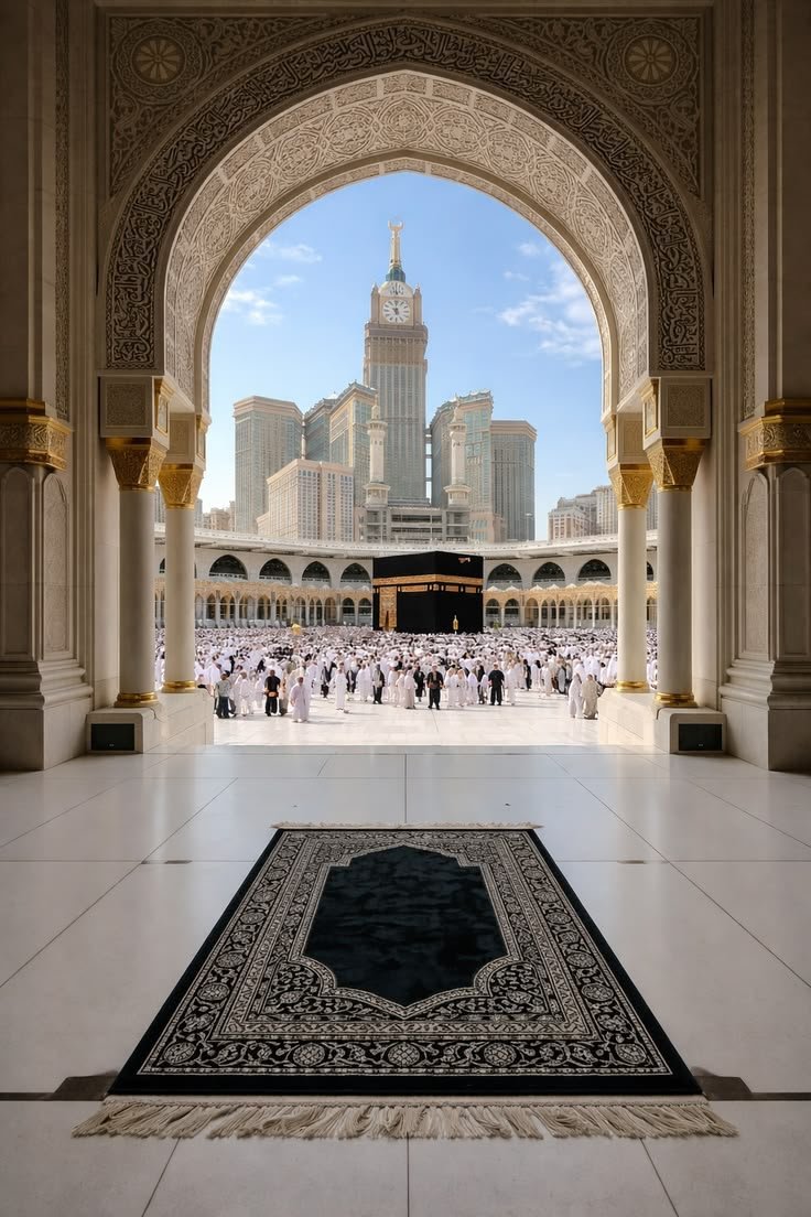 Vue de la Kaaba encadrée par une arche sculptée de Masjid Al Haram, tapis de prière au premier plan.